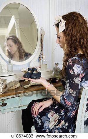 Young woman holding baby booties View Large Photo Image Stock Image - Young woman holding baby booties. Fotosearch