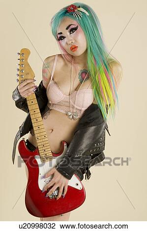 Young woman holding guitar over colored background View Large Photo Image Stock Image - Young woman holding guitar over colored background. Fotosearch