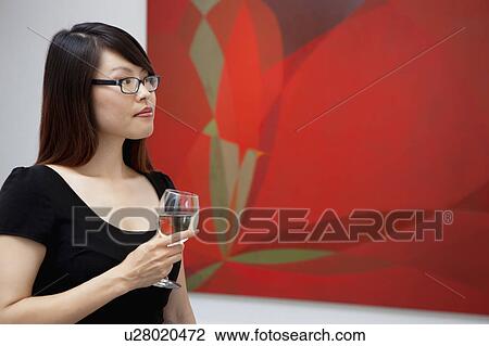 Stock Image - Young woman looking at wall paintings in art gallery. Fotosearch