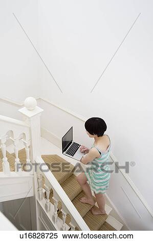 Stock Photography - Young woman walking up with laptop in hands. Fotosearch