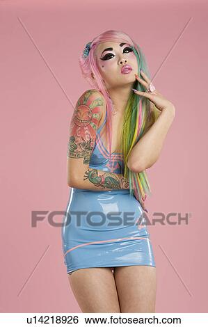 Stock Photograph - Young woman wearing party dress posing over pink background. Fotosearch