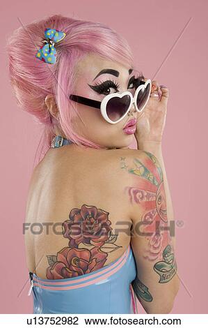 Stock Image - Young woman wearing sunglasses looking over shoulder. Fotosearch