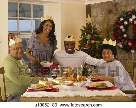 Stock Image - Adult African American family having Christmas dinner. Fotosearch