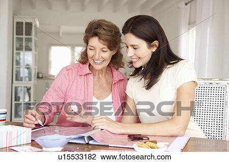 Stock Image - Adult mother and daughter scrapbooking. Fotosearch