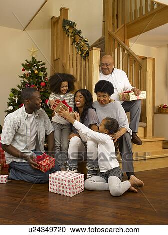 Stock Image - African American family exchanging Christmas gifts. Fotosearch
