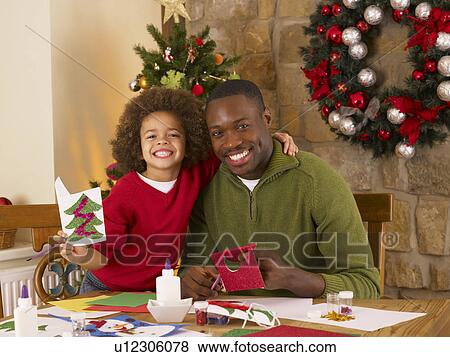 Stock Photo - African American father and mixed race son making Christmas cards. Fotosearch