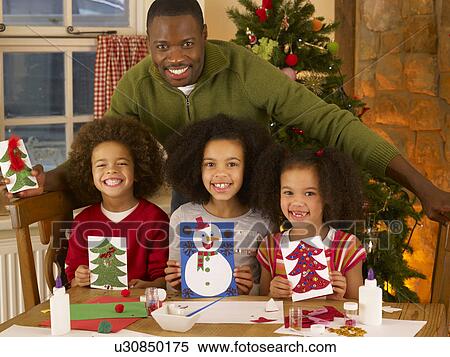 Stock Photography - African American father making Christmas cards with children. Fotosearch