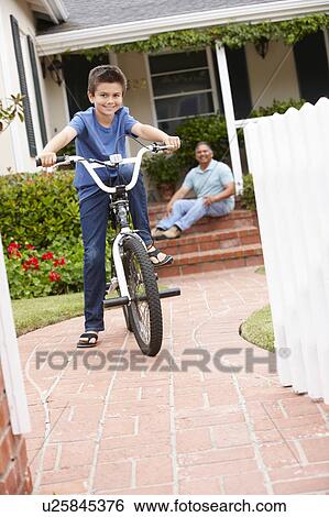 Stock Photograph - Boy and grandfather at home with bike. Fotosearch