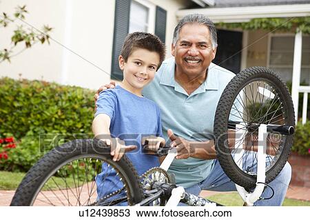 Stock Image - boy and grandfather fixing bike. Fotosearch