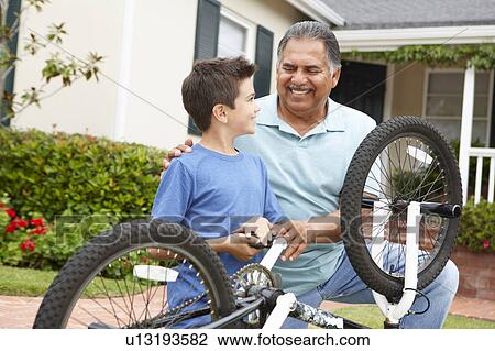 Stock Image - boy and grandfather fixing bike. Fotosearch