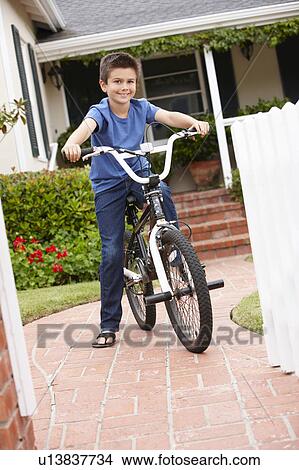 Picture - Boy in garden with bike. Fotosearch