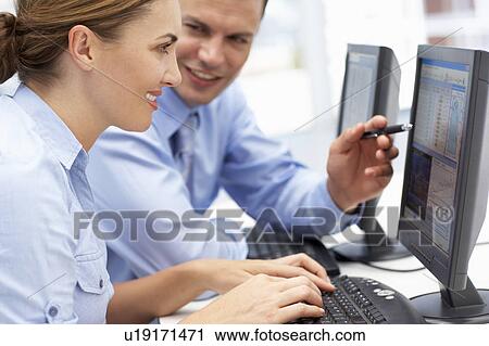 Stock Image - Business man and woman working on computers. Fotosearch