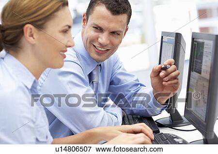 Stock Photo - Business man and woman working on computers. Fotosearch