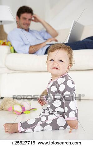 Stock Photograph - Busy father working on laptop. Fotosearch