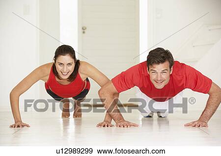 Stock Photo - Couple doing push-ups in home gym. Fotosearch