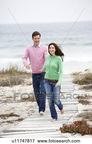 Stock Photo - Couple running along beach path. Fotosearch