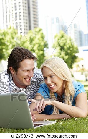 Couple using laptop in city park View Large Photo Image Stock Image - Couple using laptop in city park. Fotosearch