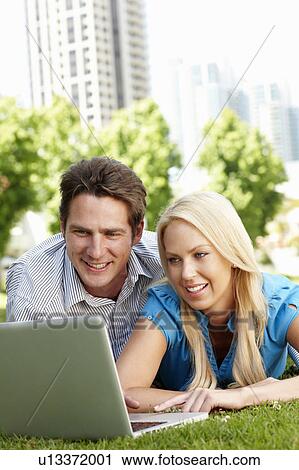 Couple using laptop in city park View Large Photo Image Stock Image - Couple using laptop in city park. Fotosearch