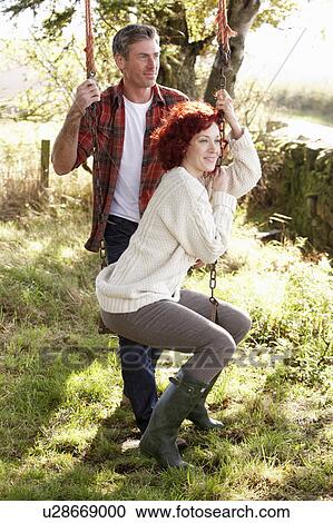 Stock Image - Couple with country garden swing. Fotosearch