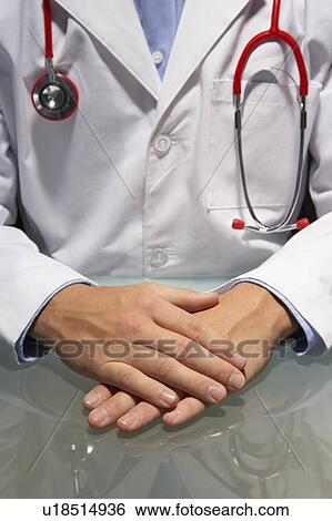Doctor sitting at desk View Large Photo Image Stock Photograph - Doctor sitting at desk. Fotosearch