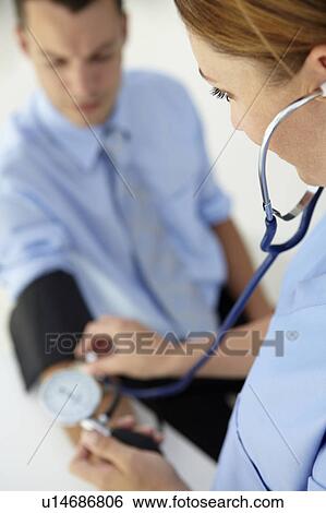 Stock Photograph - Doctor taking young man's blood pressure. Fotosearch
