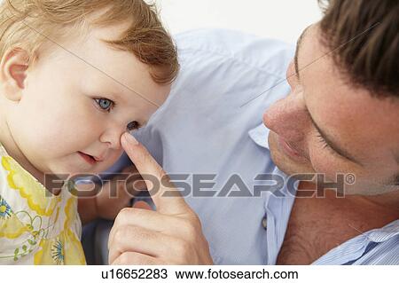 Stock Image - Doting father with baby daughter at home. Fotosearch