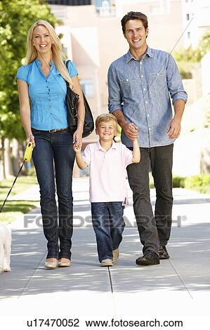 Stock Image - Family walking with dog in city street. Fotosearch
