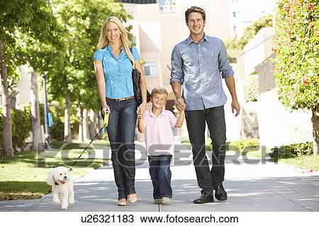 Stock Image - Family walking with dog in city street. Fotosearch