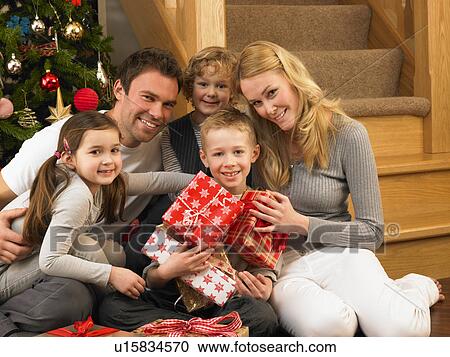 Family with gifts in front of Christmas tree View Large Photo Image Stock Image - Family with gifts in front of Christmas tree. Fotosearch