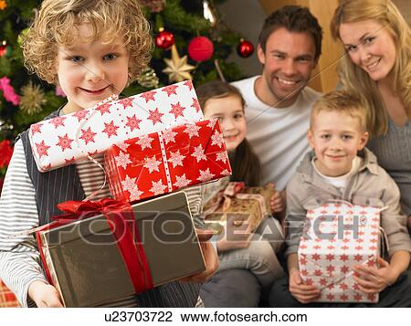 Stock Image - Family with gifts in front of Christmas tree. Fotosearch