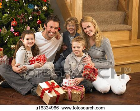 Stock Photograph - Family with gifts in front of Christmas tree. Fotosearch