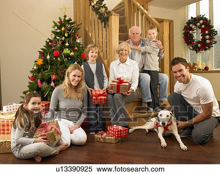 Stock Photography - Family with gifts in front of Christmas tree. Fotosearch