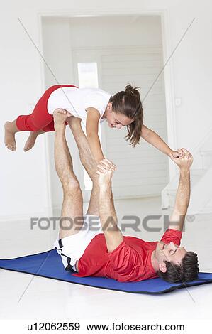 Stock Photo - Father and daughter doing yoga lift. Fotosearch