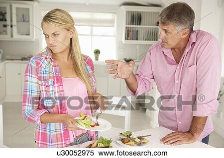 Stock Photography - Father making teenage daughter do chores at home. Fotosearch