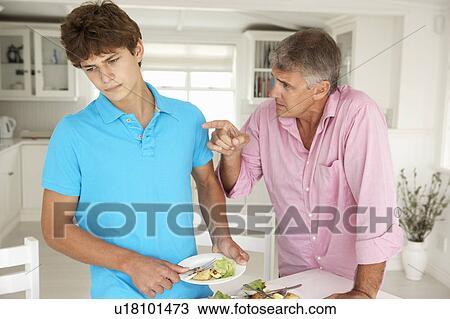 Stock Image - Father making teenage son do housework. Fotosearch
