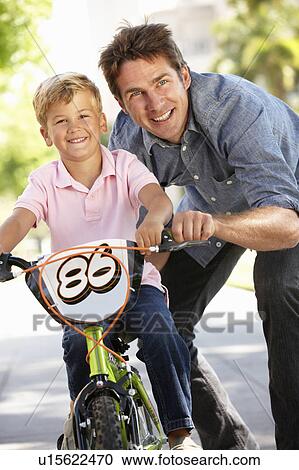Stock Image - Father with boy on bike. Fotosearch