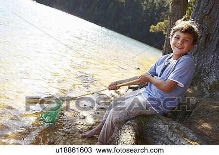Stock Image - Happy boy fishing at lake. Fotosearch