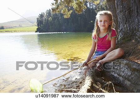 Stock Photo - Happy girl fishing at lake. Fotosearch