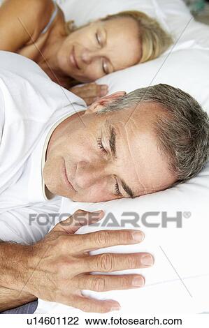 Stock Image - Head and shoulders mid age couple sleeping. Fotosearch