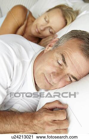 Stock Image - Head and shoulders mid age couple sleeping. Fotosearch