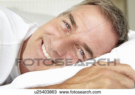 Stock Image - Head and shoulders mid age man lying down. Fotosearch