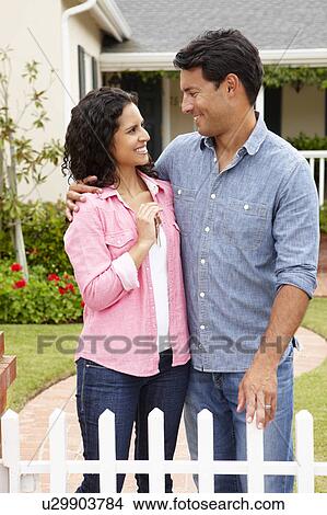 Picture - Hispanic couple outside new home. Fotosearch
