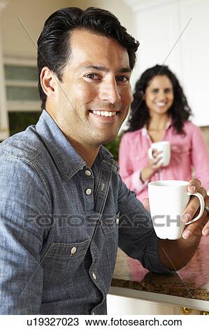 Stock Image - Hispanic couple relaxing in kitchen. Fotosearch