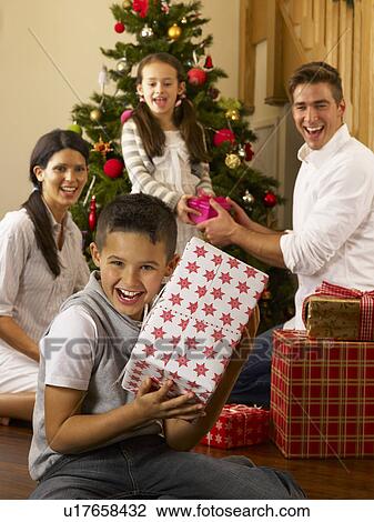 Stock Image - Hispanic family exchanging gifts at Christmas. Fotosearch