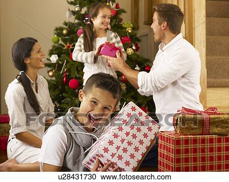 Stock Image - Hispanic family exchanging gifts at Christmas. Fotosearch