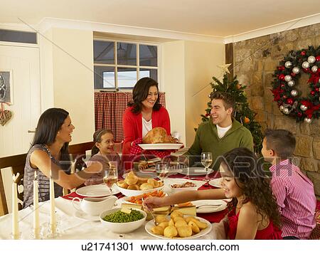 Stock Image - Hispanic family serving Christmas dinner. Fotosearch