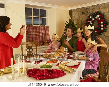 Stock Photo - Hispanic family taking photos of Christmas dinner. Fotosearch