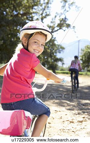 Stock Photography - Little girl on country bike ride with mom. Fotosearch