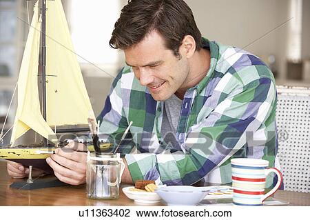Stock Image - Man making model ship. Fotosearch