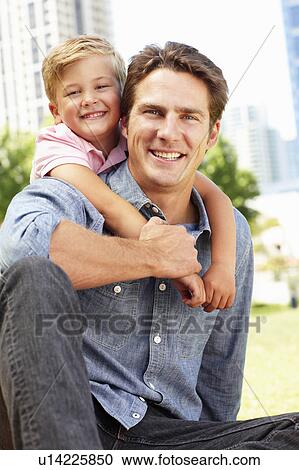 Stock Image - Man sitting in city park with young son. Fotosearch